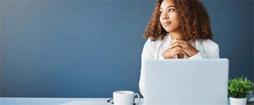 woman sitting at a laptop looking into distances as if she wereworking on a solution